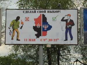 Placa com a frase “Faça sua escolha!” em russo com alguns desenhos que influenciam o leitor sobre qual lado escolher.